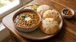 Black-eyed pea curry served with three puffed puris, sliced onions, and lime.